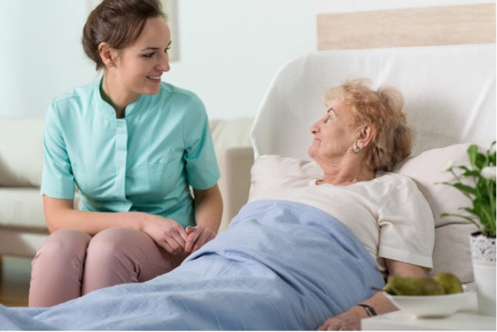 women sitting by older lady in bed